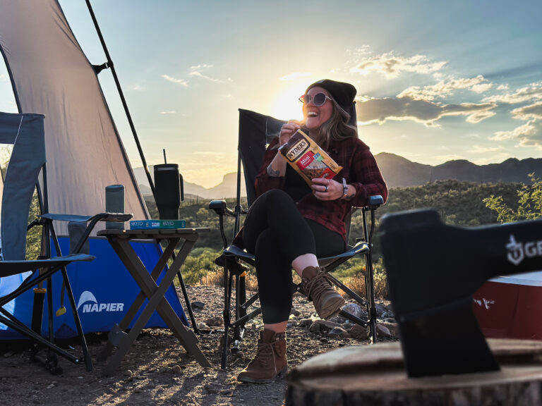 Woman smiling outdoors at a campsite.